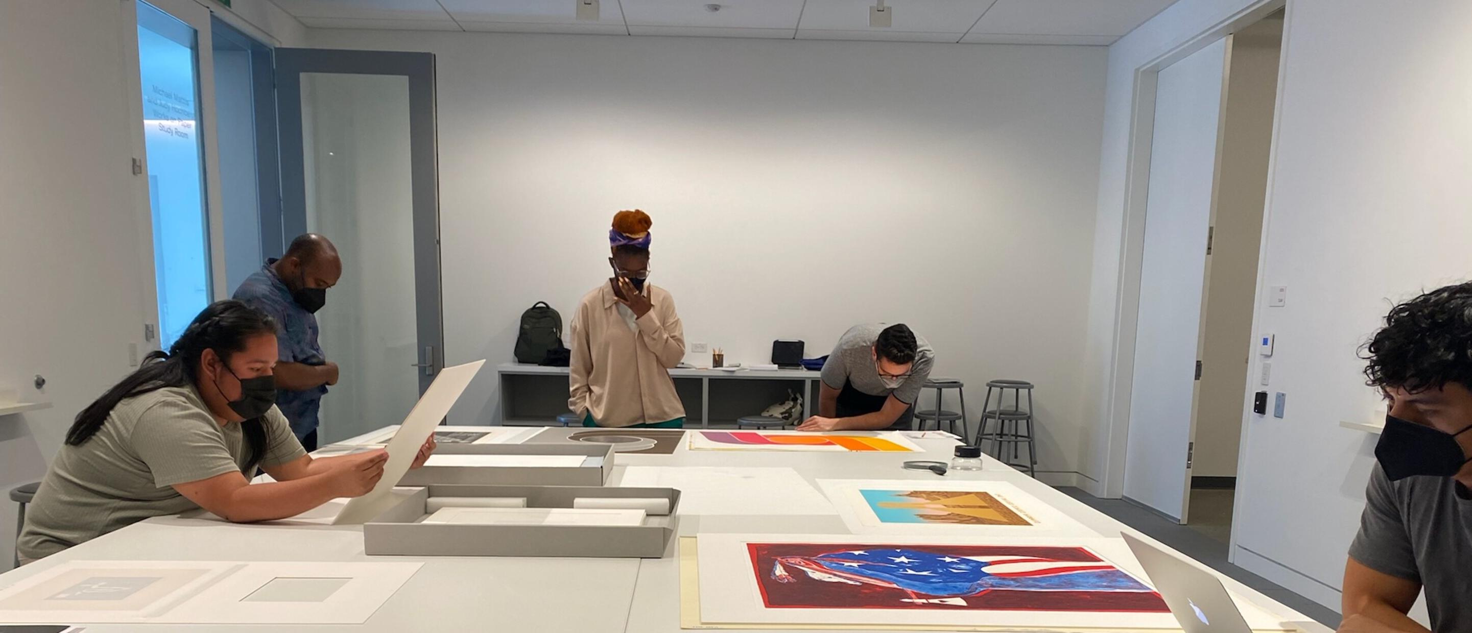 5 people looking at prints on a large table